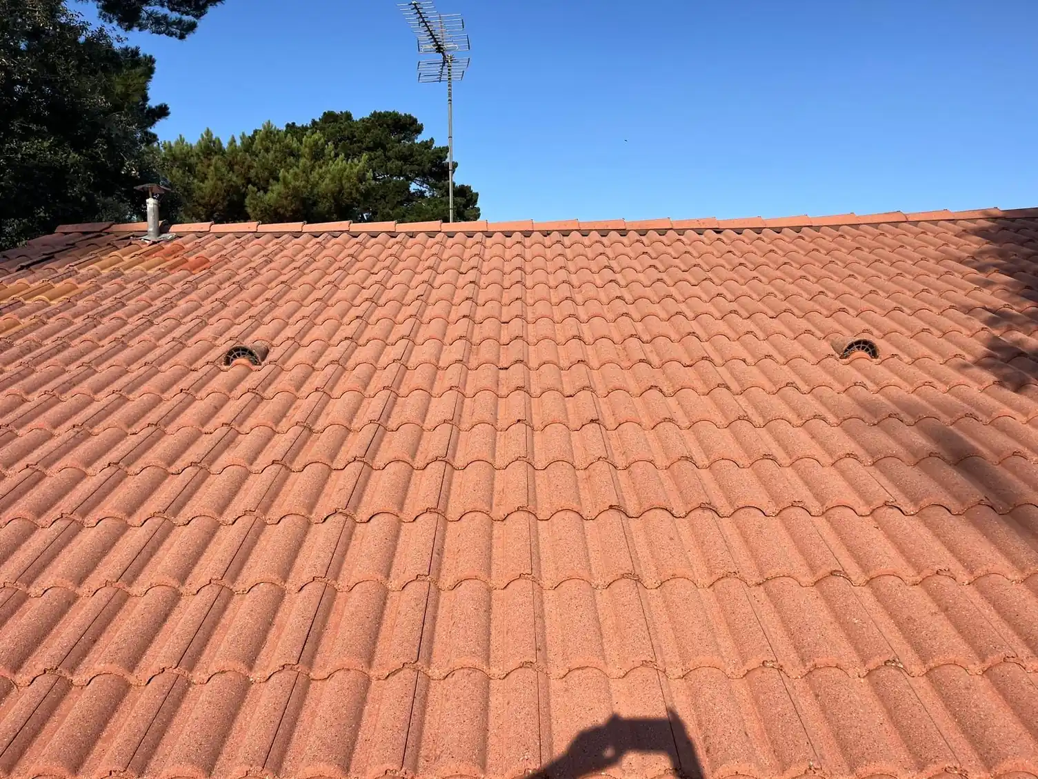 Versant en tuiles orange après traitement, sous un ciel dégagé