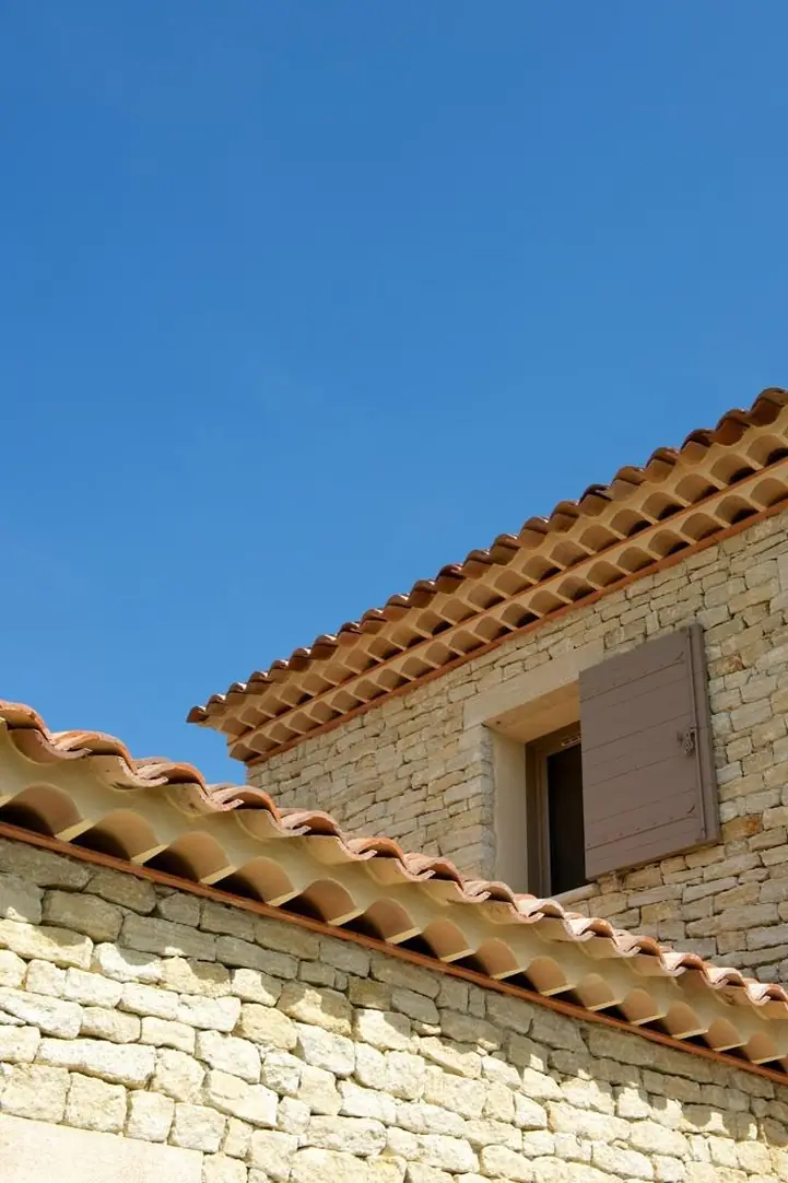Toiture en tuile canal sur une maison de pierre, ciel bleu