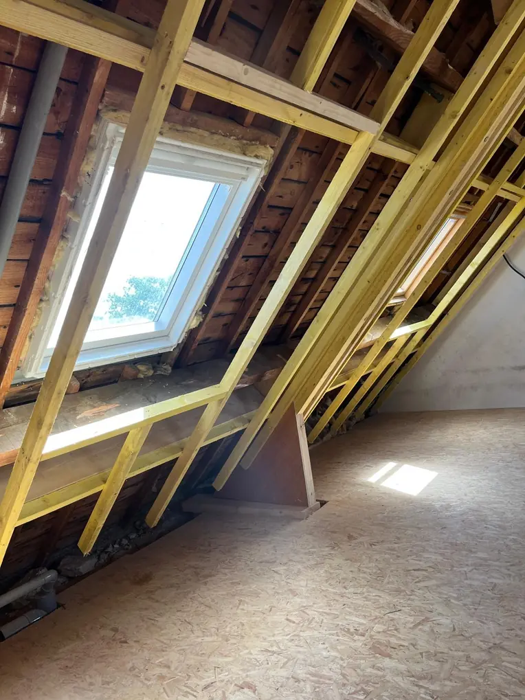 Comble aménagé éclairé par une fenêtre de toit, ossature bois visible
