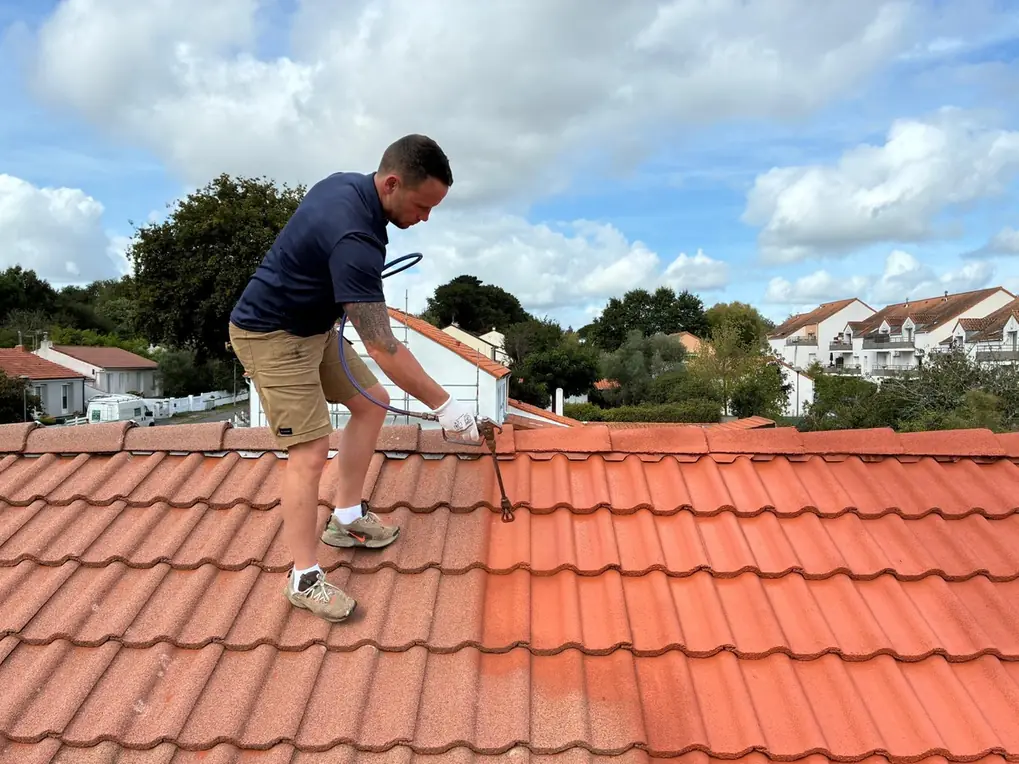 Couvreur appliquant un traitement sur un versant, lance basse pression