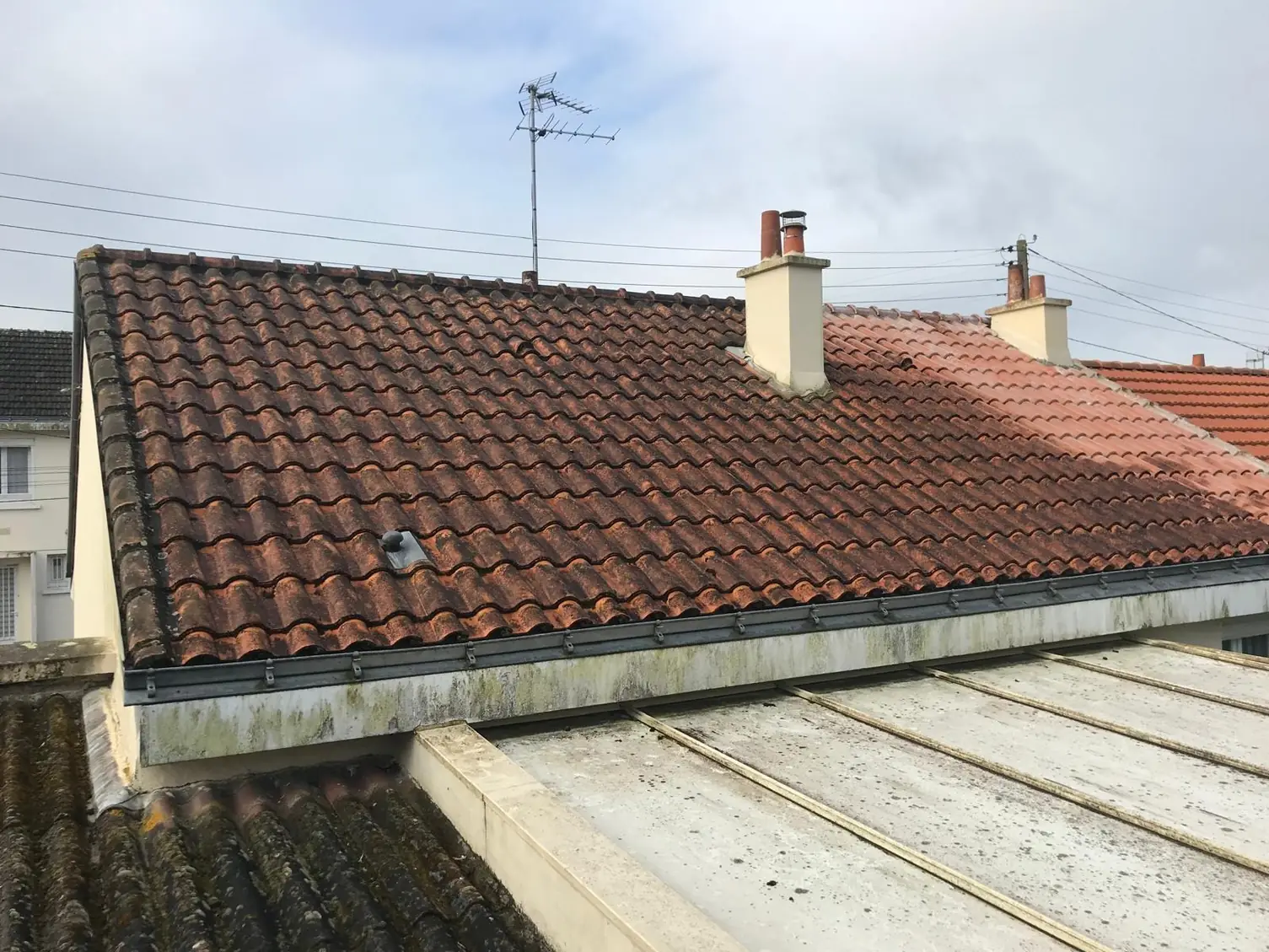 Toiture en tuiles avec antenne, maisons voisines en arrière-plan
